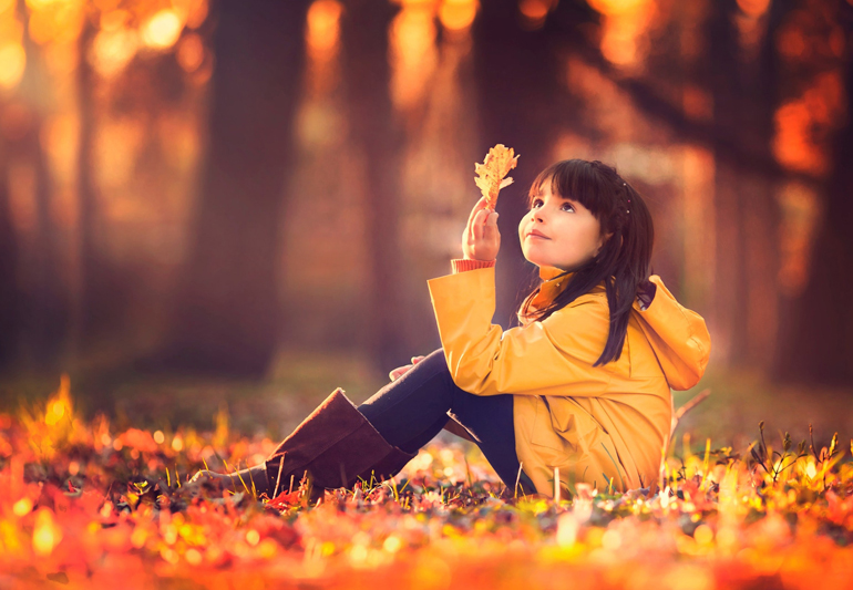 девочка смотрит на лист осенью