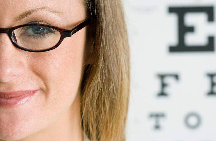 девушка в очках на фоне таблицы для проверки зрения