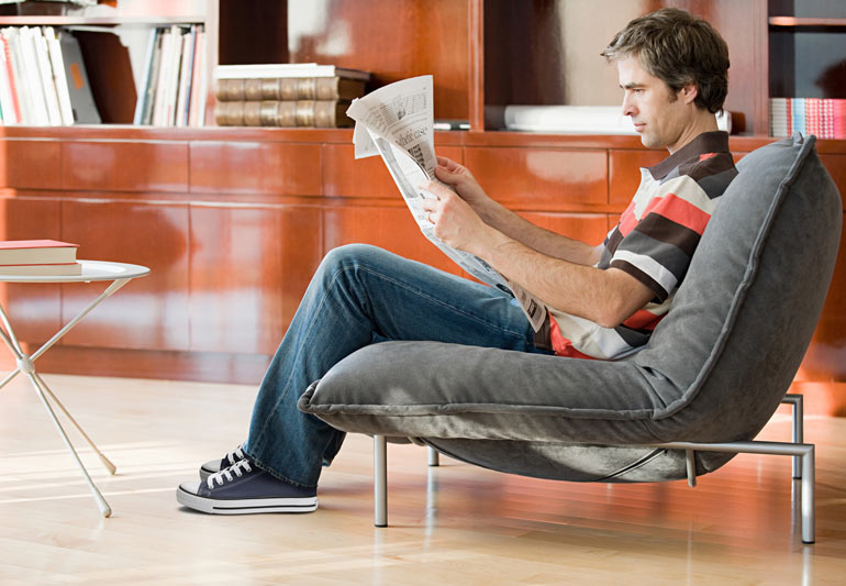 мужчина в кресле читает газету